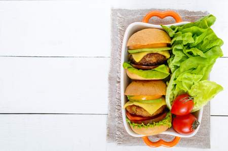 Sandwiches (burgers) with yellow and black tomatoes, juicy cutlet, avocado on a white wooden background. The top view. Empty space for your notes and projects.の写真素材