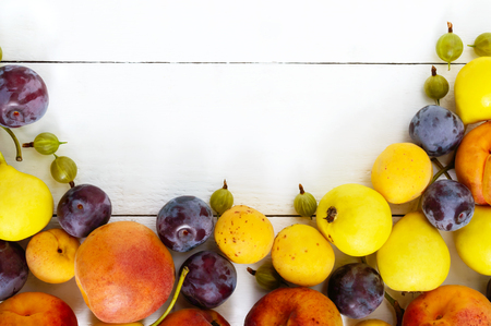 A pile of juicy summer fruits on white wooden table (plums, apricots, pears). Harvest from the garden. A natural source of vitamins. Food background.の写真素材
