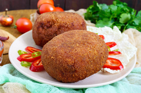 Juicy golden cutlets stuffed with boiled egg on a wooden background.