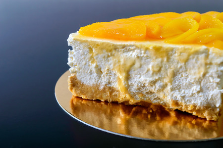 Delicate souffle with juicy peaches. A large delicious piece of cake on a golden stand on a black background.の写真素材