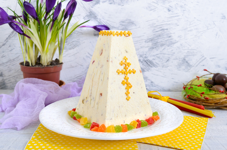 Traditional curd Easter cake with candied fruits and chocolate eggs, spring flowers crocus on the...