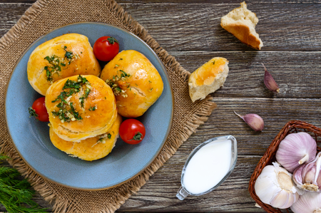 Soft buns with herbs and garlic with sour cream on a wooden background. Top view.の写真素材