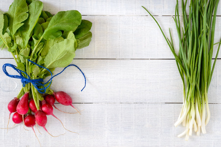 Fresh red radishes and green young onions on white wooden background.  Healthy diet with radish. Ingredients for a light spring vegetable salad. Free space for an inscription.の写真素材