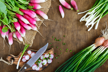 Sliced fresh red radishes and green young onions on white wooden background.  Healthy diet with radish. Ingredients for a light spring vegetable salad. The top viewの写真素材