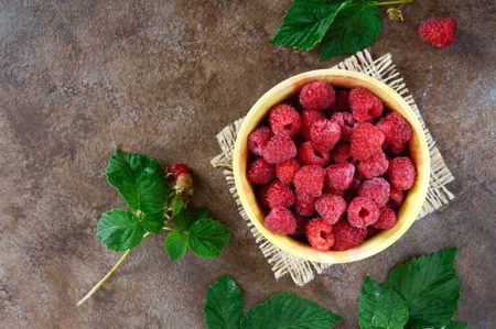 Fresh ripe tasty raspberries in a yellow ceramic bowl. Summer berries. Top view.