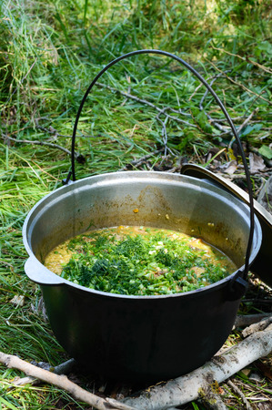 Delicious porridge cous cous with meat, vegetables and fresh herbs in a pot cooking on the nature.の写真素材