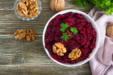 Boiled beetroot with nuts in a white bowl on a wooden background. Top view.の写真素材