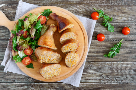 Tasty stuffed chicken legs with salad of fresh vegetables on a wooden background. Rolls with chicken and vegetables. Top view.の写真素材