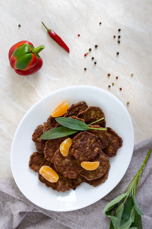 Tasty liver cutlets with tangerines on a white plate on the table. Top view.の写真素材