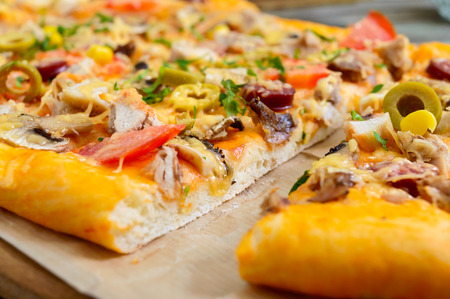 Tasty pizza with mushrooms, chicken, pepperoni, olives, corn cut into pieces. Close upの写真素材
