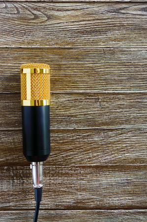 Condenser gold microphone lies on a wooden table with copy space. Musical theme. Flat lay. Top view.の写真素材