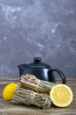Organic dry lemongrass (Cymbopogon flexuosus) in bunches and lemon fruit on a wooden table. Herbs for tea.の写真素材