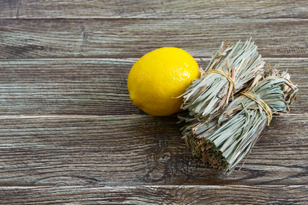 Organic dry lemongrass (Cymbopogon flexuosus) in bunches and lemon fruit on a wooden table. Herbs for tea.の写真素材
