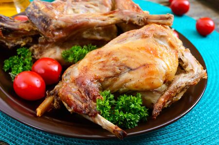 Whole baked rabbit with greens and tomatoes on a plate. Tasty dietary meat.の写真素材