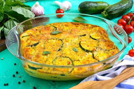 Zucchini, cheese, eggs, cream and green casserole in a glass dish on a bright background. Tasty healthy dish.の写真素材