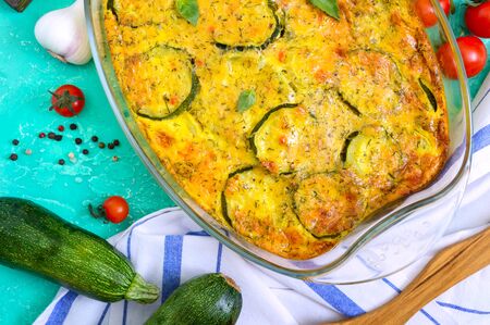 Zucchini, cheese, eggs, cream and green casserole in a  glass dish on a bright background. Tasty healthy dish. Top view, flat lay.の写真素材