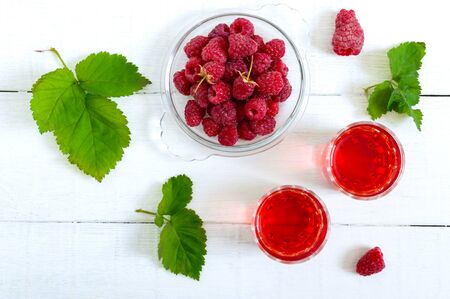 Raspberry liqueur in glass and fresh berries on a white background. Alcoholic flavored drink. The...