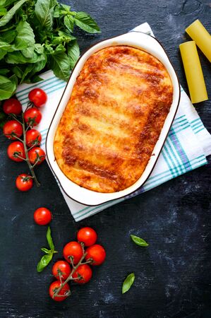 Stuffed cannelloni with bechamel sauce. Cannelloni pasta baked with meat, cream sauce, cheese on a black background. Top view, flat lay.の写真素材