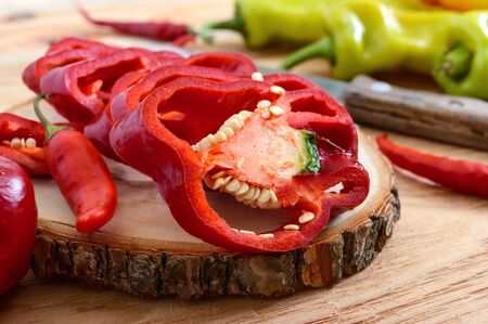A pile of whole and chopped pepper on a wooden table. Hot and sweet green, orange, red peppers. Rustic style. Top view.A pile of whole and chopped pepper on a wooden table. Hot and sweet green, orange, red peppers. Rustic style.の写真素材