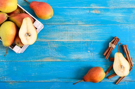 Ripe rosy pears in a wooden box on a blue background. Autumn harvest of fruits. Top view. Food background. Copy spaceの写真素材