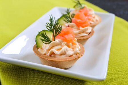 Tartlets with cream cheese and salted salmon on a white plate. Tasty light snack for a party. Finger Food.の写真素材