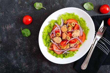Salad of marinated mussels, fresh tomatoes, red onions, olives in a bowl on a black backgroundの写真素材