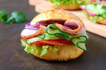 Homemade bun with ham, vegetables, herbs on a wooden board.  Sandwich for lunch. Close upの写真素材