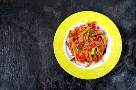 Korean eggplants. Spicy vegetable salad with eggplant, bell peppers, carrots, onions on a plate on a...
