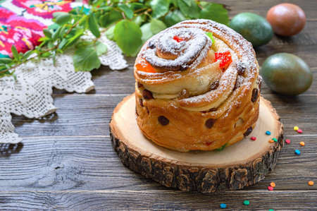Sweet Easter cake, painted eggs, green branches on a wooden table. Spring holiday background with copy spaceの写真素材