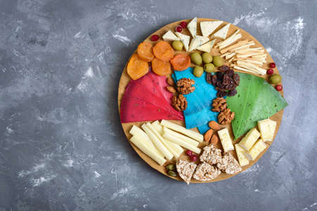 Different kinds of cheeses, dried apricots, whole-grain breads, nuts, olives, capers on a wooden board. Cheese board, snacks. Copy space. Top viewの写真素材