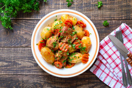 Roast turkey, potatoes, carrots and fresh parsley in a bowl on a wooden background. Useful and nutritious dish. Top view.の写真素材