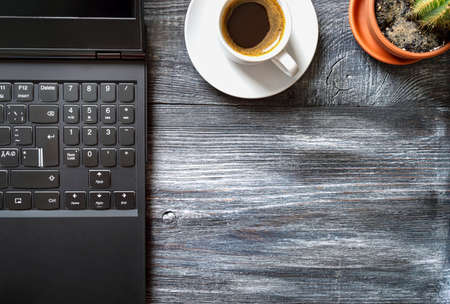 Workplace with laptop, cup of coffee, cactus on a wooden table, top view, flat lay with copy space....
