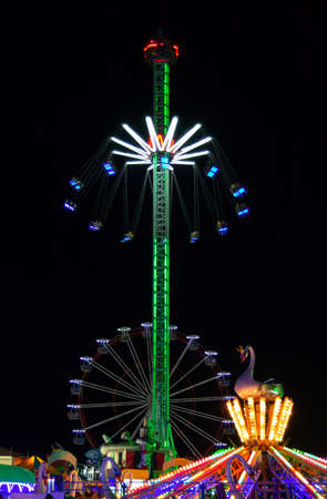 View of the night amusement park. Ferris wheel, bright carousels.の写真素材