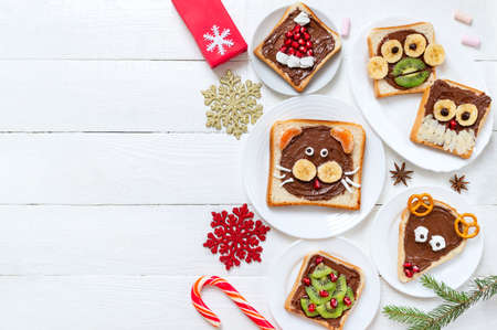 Assorted funny sandwiches with chocolate, fresh fruit, marshmallows on plates, top view. The idea of a menu for a children's party. Creative breakfast, Christmas theme. Copy spaceの写真素材