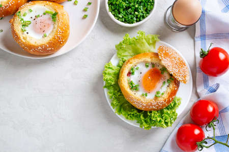 Egg baked in a soft bun with ham. Delicious and quick breakfast. Top view with copy space.
