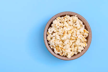 Bowl of tasty popcorn on a blue background. Top view with copy space.の写真素材
