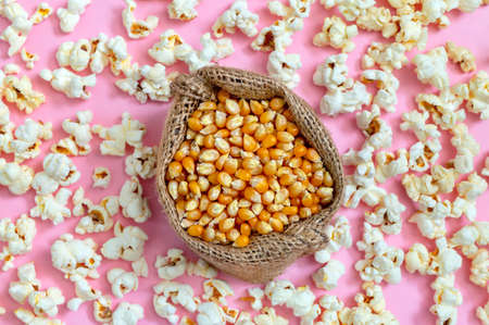 Corn grains in a bag. Scattered popcorn on a pink background. top view.の写真素材