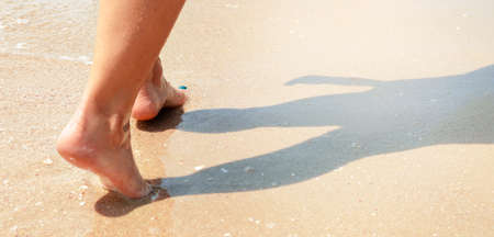 Female feet step on the sea wave. Summer holidays concept. Banner with copy space.