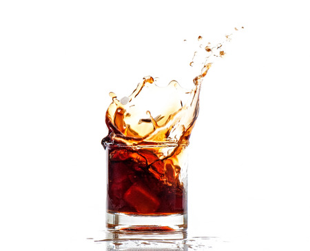 splash of cola in glass isolated on white background