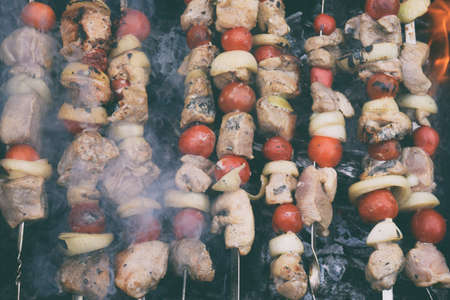 Grilled kebab cooking on metal skewers grill . Roasted meat cooked at barbecue with smoke. Traditional eastern dish, shish kebab. Grill on charcoal and flame, picnicの写真素材