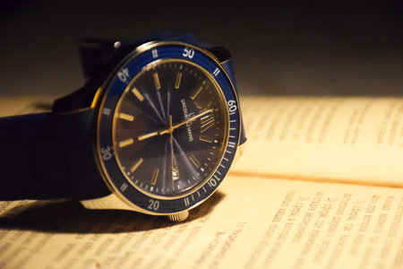 Beautiful gold men's watch with a black strap on a wooden stand, on a gray background. Beautiful...