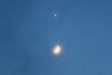 Crescent moon visible in a clear blue sky