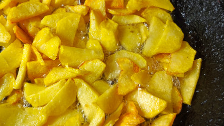 Tasty crispy fried wedges of potato with fresh rosemary served in an old metal skillet in a close up wide angle viewの写真素材