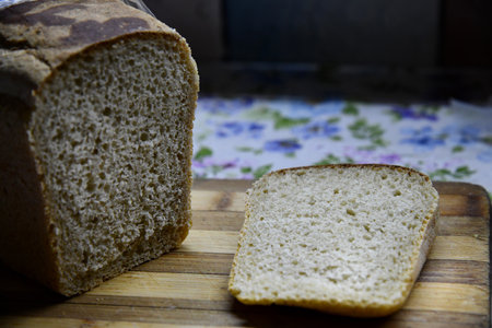 Rustic sourdough bread with cut slices on a wooden table on black background with free space for textの写真素材