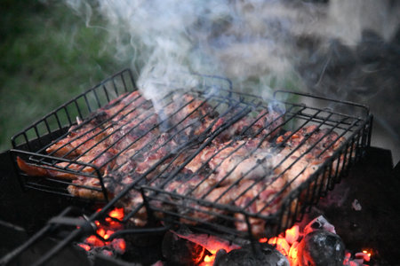 Grilled meat steak on stainless grill depot with flames on dark background. Food and cuisine concept.の写真素材