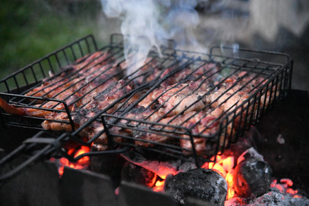 Grilled meat steak on stainless grill depot with flames on dark background. Food and cuisine concept.の写真素材