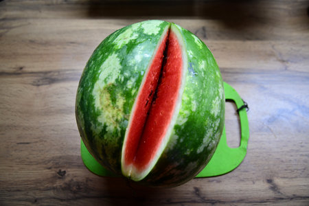 Freshly sliced watermelon revealing juicy red flesh on wooden tableの写真素材