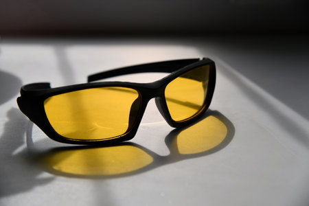 Flat lay composition of black framed glasses on yellow background.
