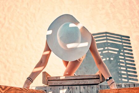 Young girl in swimsuit and white hat on the beach lifeguard tower
