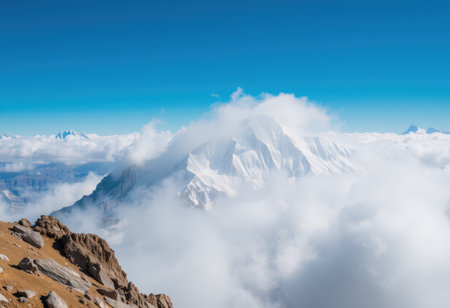 A snowy mountain peak rises through a sea of clouds, creating a breathtaking landscape under a clear blue sky.の素材